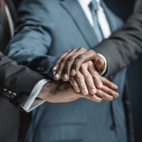 cropped shot of multiethnic group of businessmen holding hands together